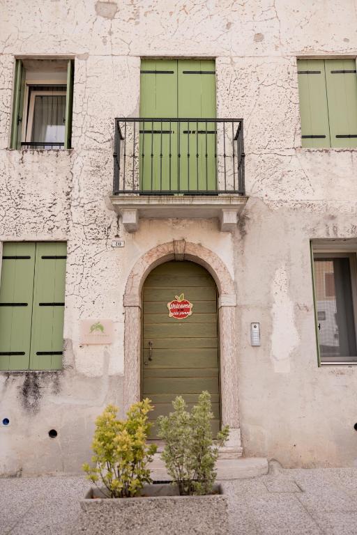 a building with a green door and a balcony at locazione turistica PetitePomme in Borso del Grappa
