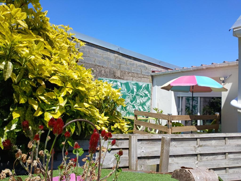 a garden with a wooden fence and an umbrella at Chez Isa in Saint-Martin-Boulogne
