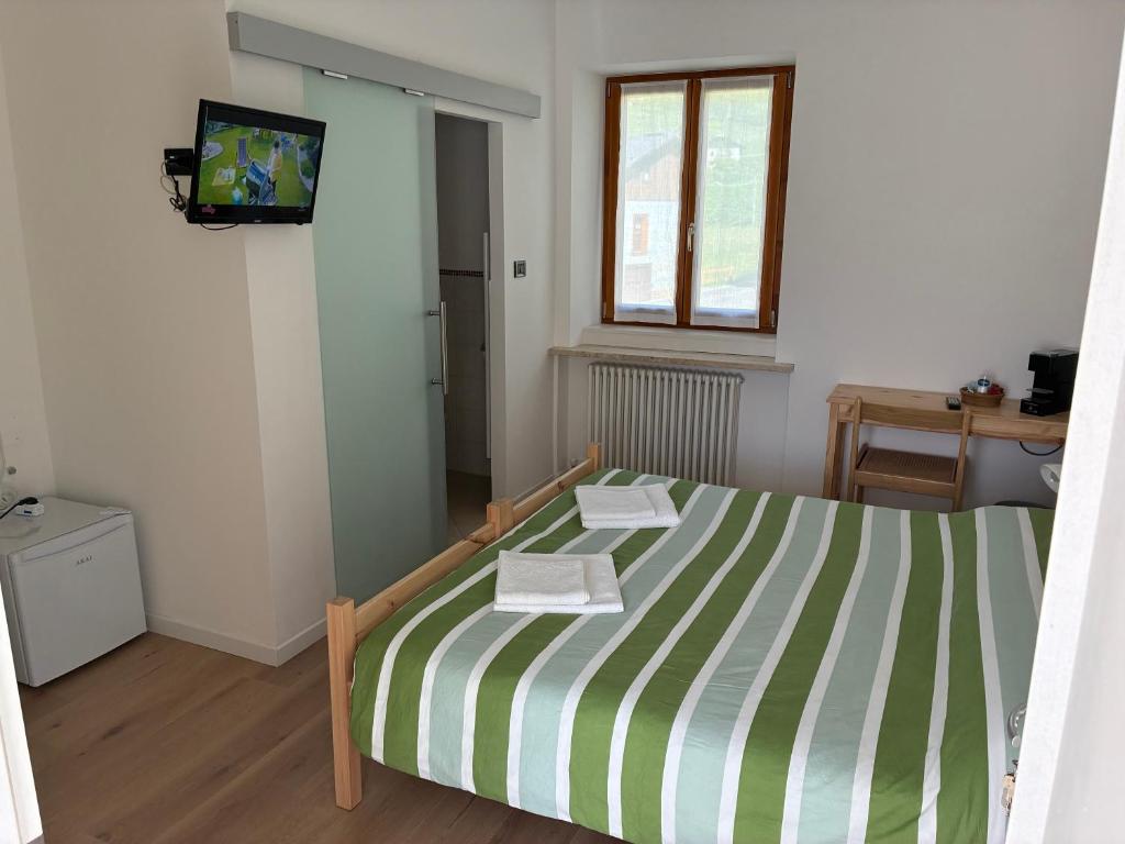 a bedroom with a bed with a green and white striped sheets at Affittacamere Penasa in Rabbi