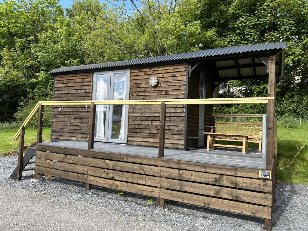 a wooden cabin with a porch and a bench at Tower Farm Holidays - Glamping in Llangollen