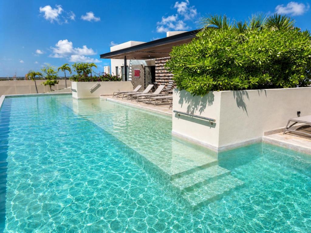 a swimming pool with blue water in front of a house at Syrena Luxury Caribbean - Heart of Playa del Carmen - Sea Views in Playa del Carmen