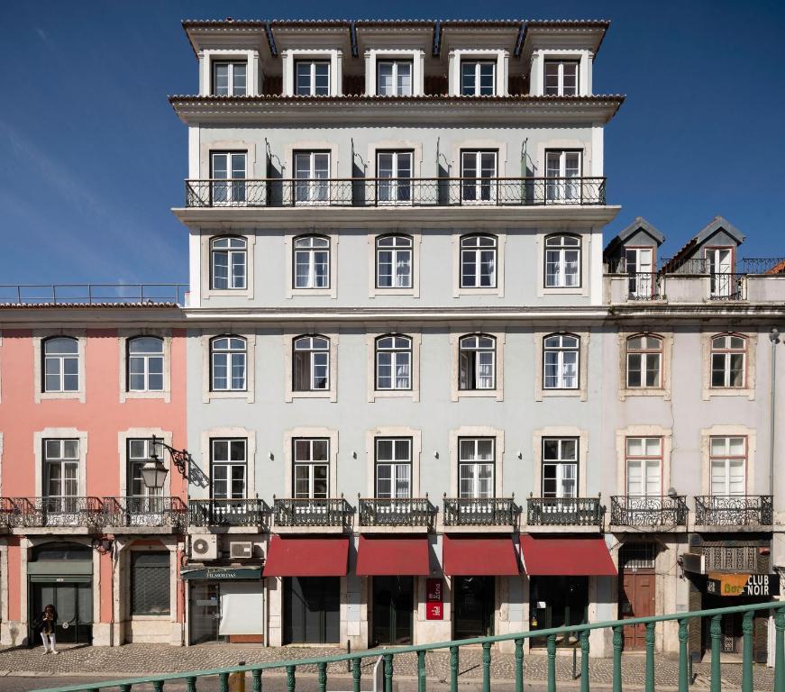 a large white building with balconies on top of it at Esqina Cosmopolitan Lodge in Lisbon