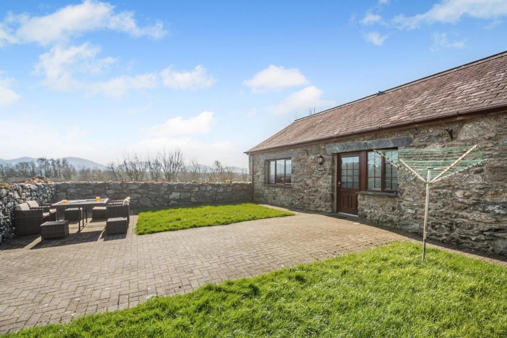 a stone house with a patio and a table at 3 Bed in Llanfairpwll oc-22999 in Llanfairpwllgwyngyll