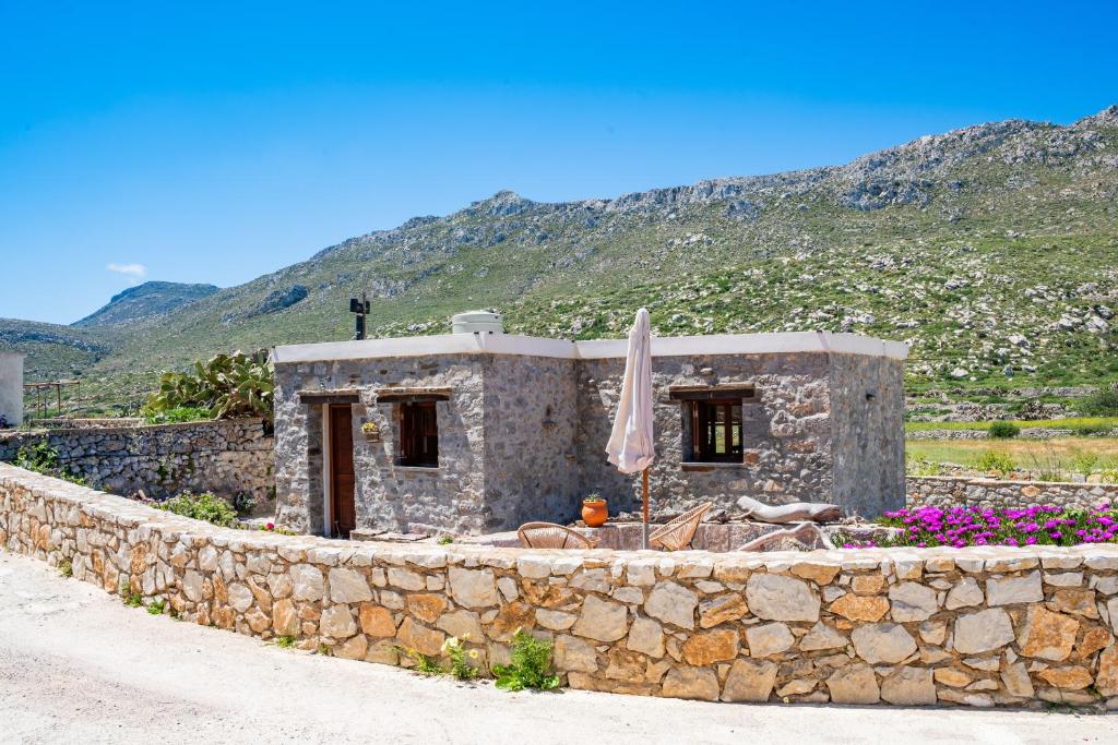 a stone building with an umbrella and a stone wall at Lithos House in Avlóna