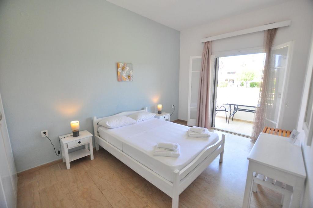 a white bedroom with a bed and a balcony at Alexandra On The Beach in (( Litherés ))