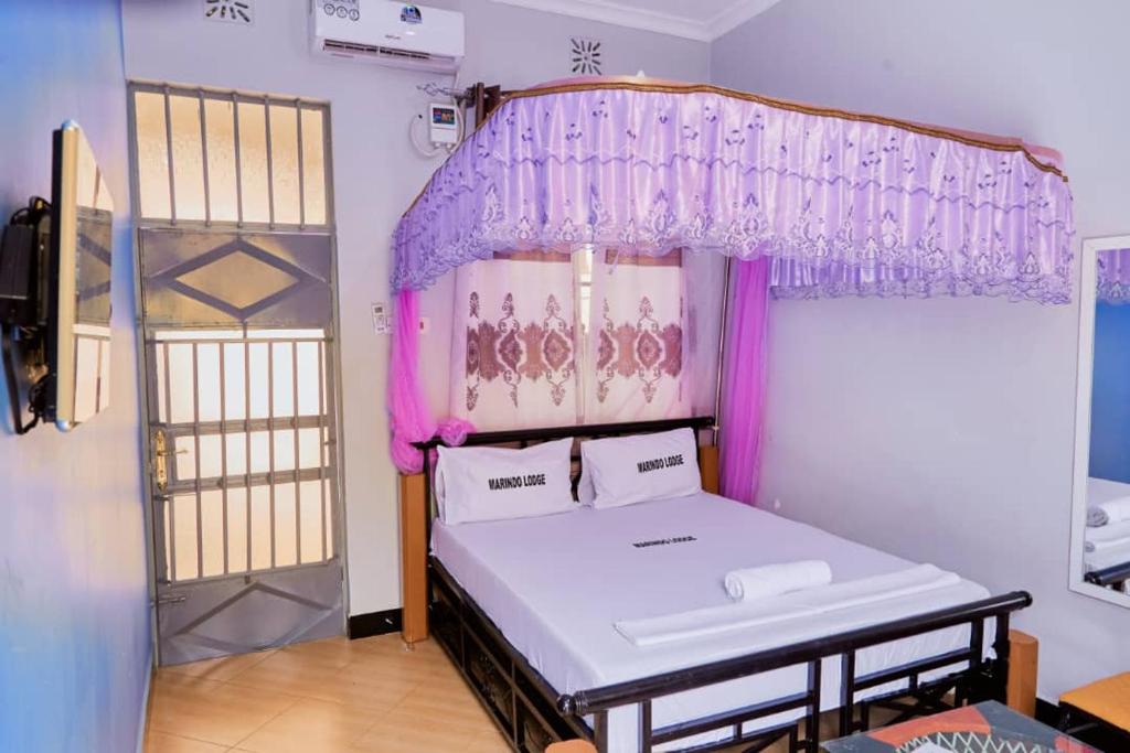 a bedroom with a bed with a purple canopy at Marindo Lodge Moshi in Moshi