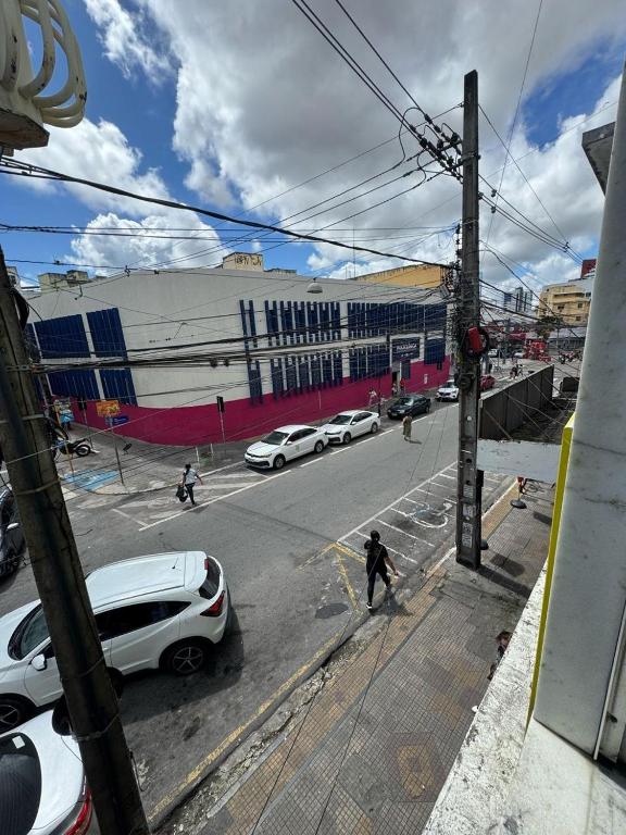 a man walking down a street with cars parked on the street at hotel vitoria in Campina Grande