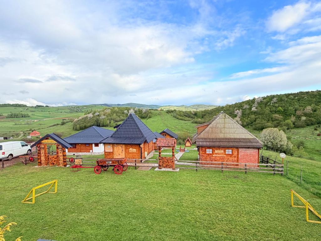 a group of wooden buildings in a grassy field at ETNO SELO VEZIROV RANČ in Sjenica