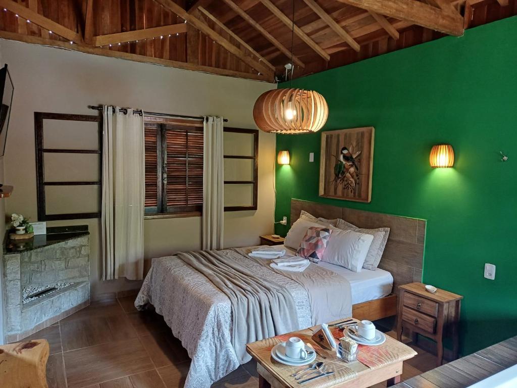 a bedroom with a bed and a green wall at Pousada Recanto Lajinha - Chalé Amor Eterno in Visconde De Maua