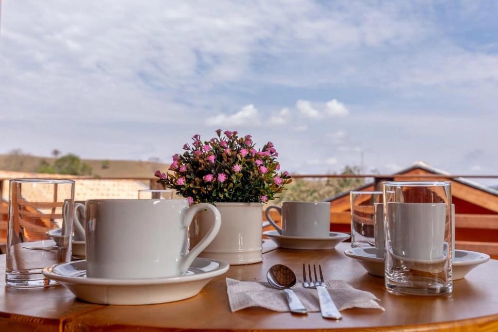 a table with cups and plates and a vase of flowers at Pousada Vale Verde com café da manhã in Lindóia