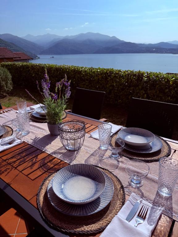 a table with plates and glasses and a view of the water at Perla di Lago Maggiore in Oggebbio