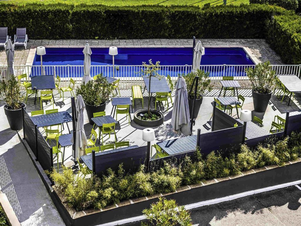 a patio with chairs and tables and a pool at ibis Styles Chalon sur Saône in Chalon-sur-Saône