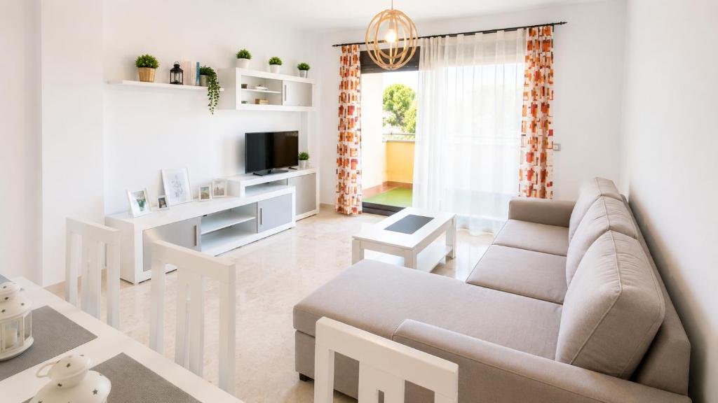 a white living room with a couch and a tv at LyriosHomes Beach Costa Ballena in Chipiona