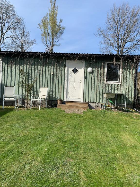 a green building with a white door and a yard at Örkelljunga cottage in Orkelljunga