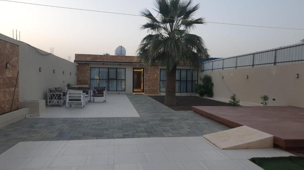 a courtyard with a palm tree and a building at شاليه مرزوقة in Buraydah