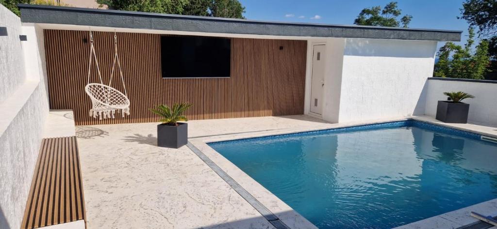 a swimming pool in a backyard with a swing and a house at Villa Maja in Sutomore