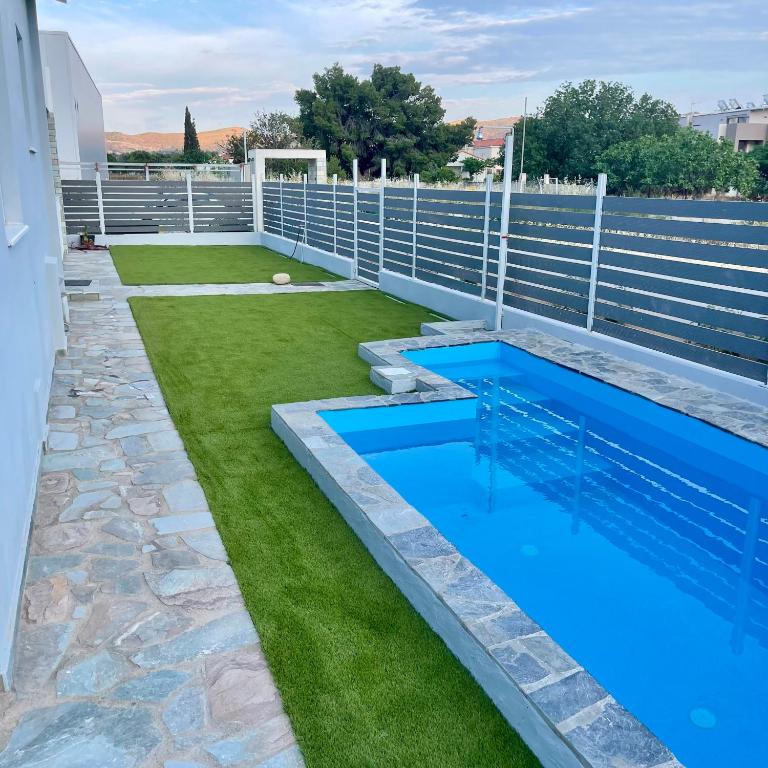a swimming pool with blue water and grass at Casa Anavyssos in Anavyssos