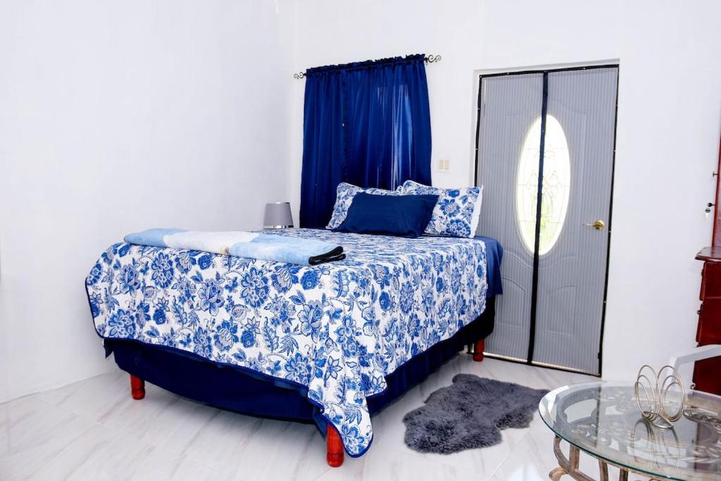 a bedroom with a blue and white bed with a glass table at Sharays Hideaway in Bull Bay
