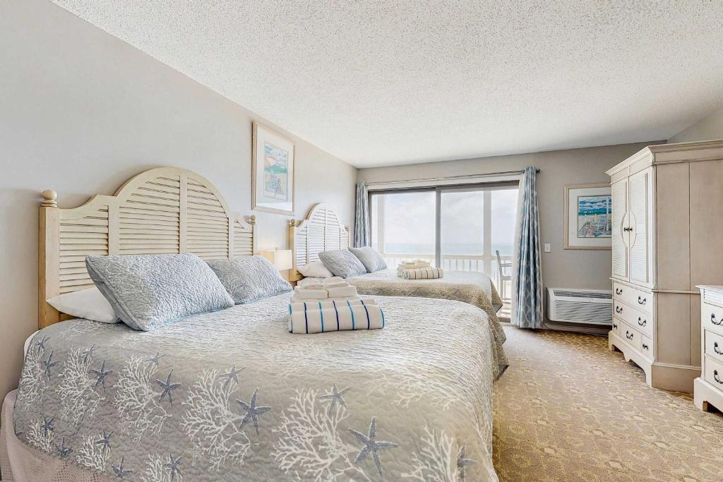a bedroom with two beds and a large window at Oceanfront suite with bay views full kitchen balcony AC & firepit in North Truro