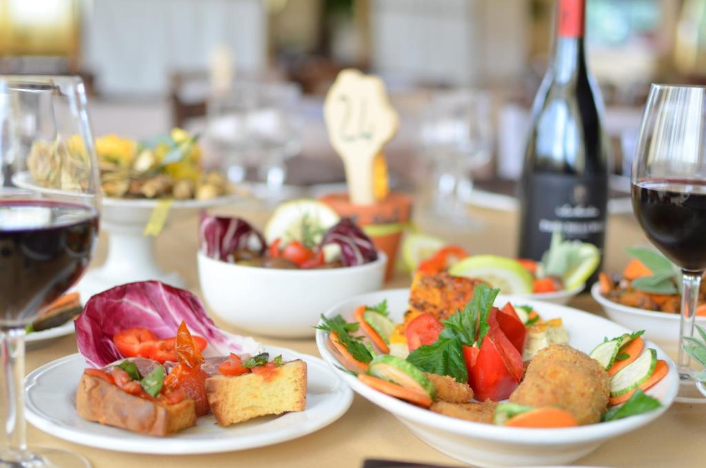 einen Tisch mit Teller mit Speisen und Gläsern Wein in der Unterkunft Il Giardino Del Sole in Agnone Bagni