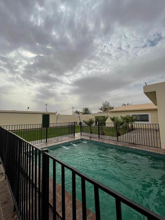 a swimming pool with a fence next to a building at استراحة لايك لاين ديراب in Ar Riyāḑ