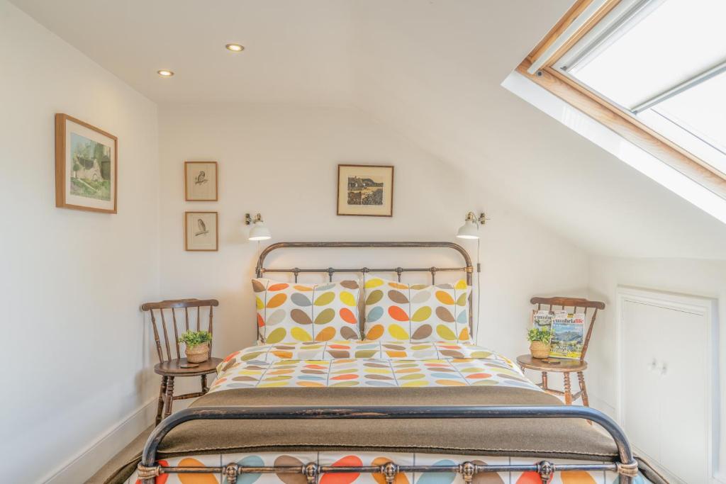 a bed in a room with two chairs and a window at North View B&B in Penrith