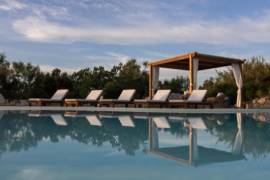 a group of lounge chairs next to a swimming pool at Masseria Tenuta Specolizzi in Lido Marini