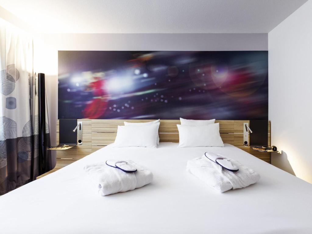 a bedroom with a bed with two white pillows at Novotel Limoges Le Lac in Limoges