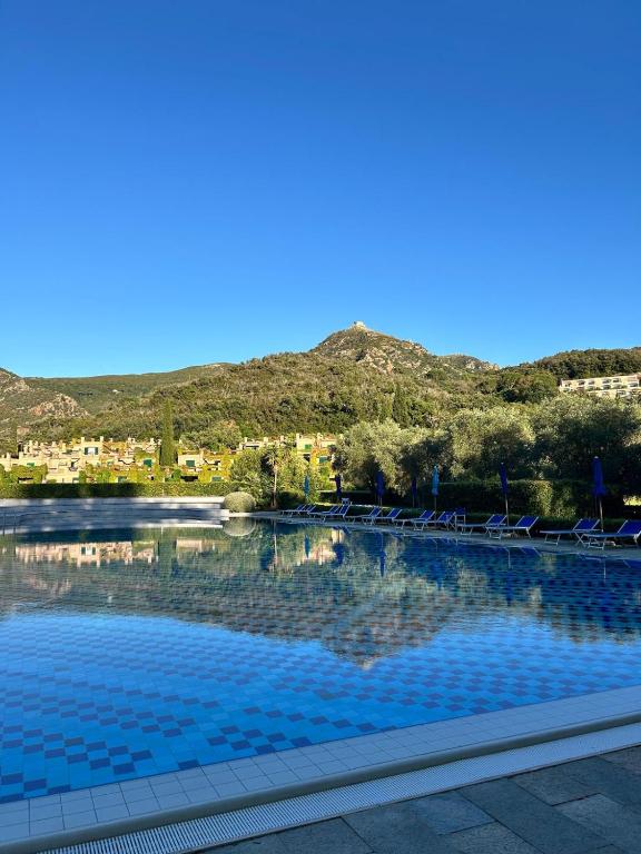a swimming pool with chairs and a mountain in the background at Dimora degli Ulivi in Bagnaia