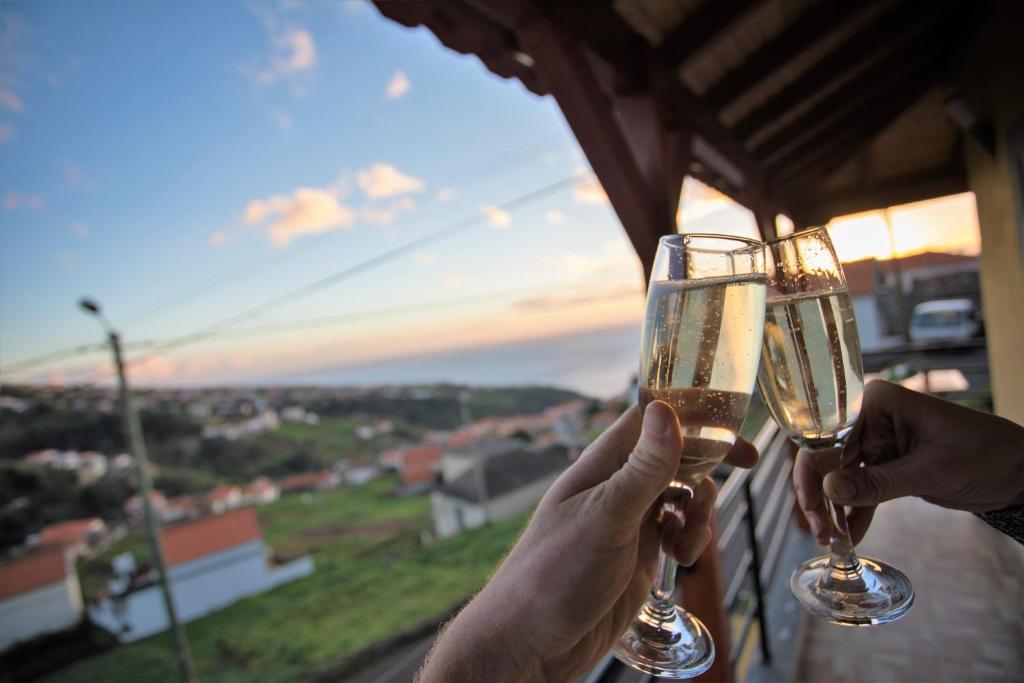 two people holding up wine glasses in front of a window at Orchid House Madeira in Calheta