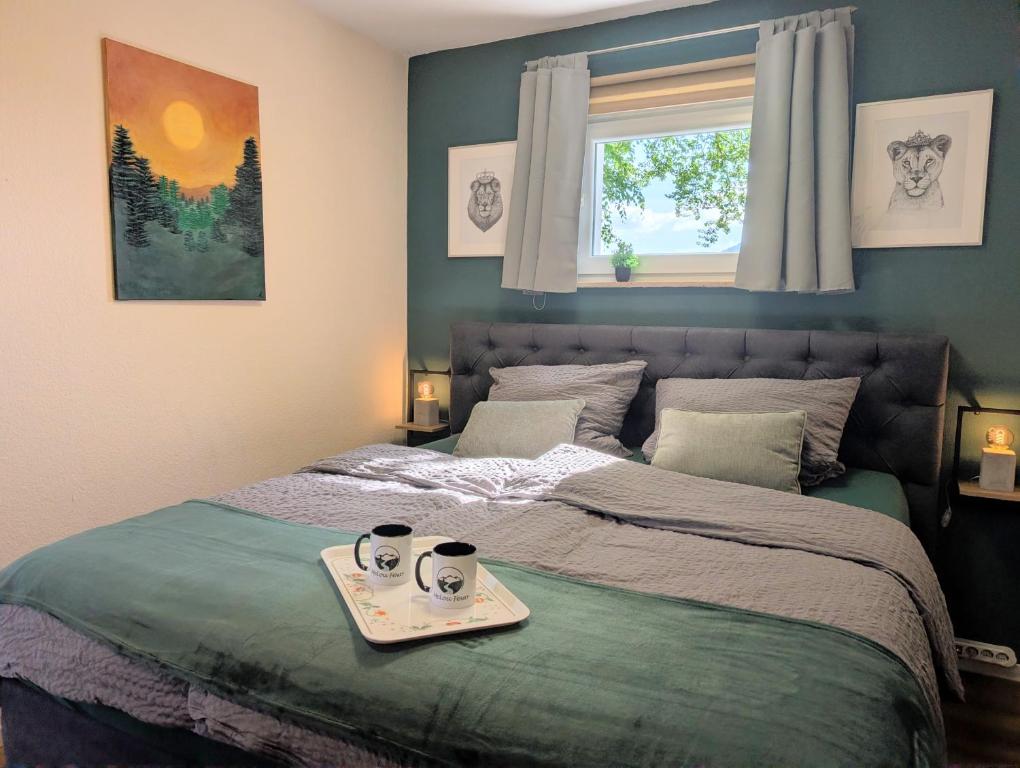 a bed with a tray with two cups of coffee on it at MeLou FeWo NaturQuartier Wellness in Bad Lauterberg
