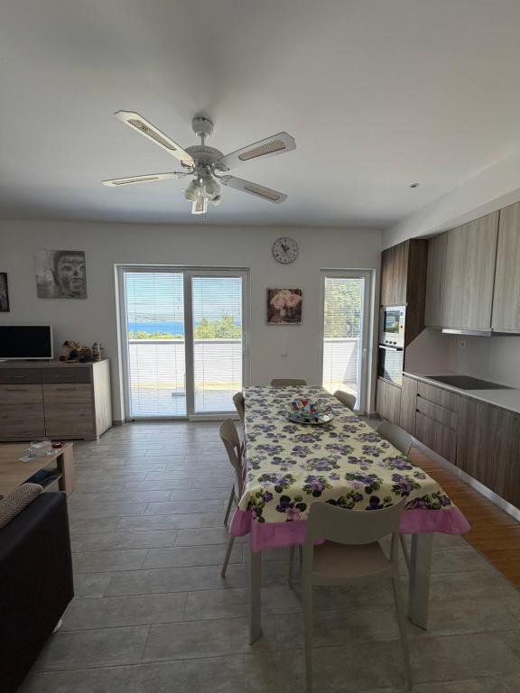 a dining room with a table and a ceiling fan at Apartman Aloe in Mali Lošinj