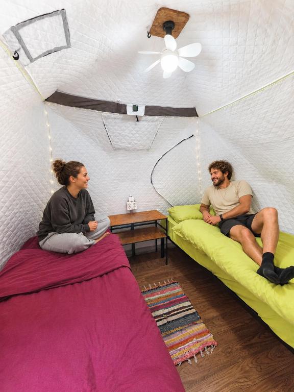 two people sitting on beds in a room at Friends glamping & Sauna in Kutaisi