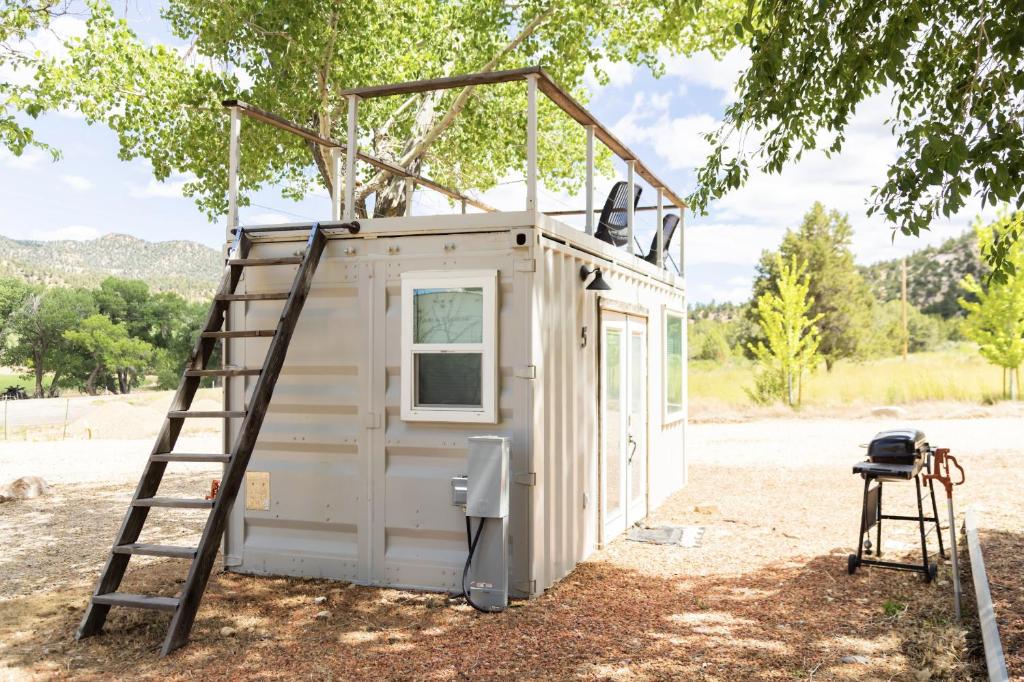 a tiny house with a ladder next to a tree at NEW! Cozy Container Home at Cliffside #5 in Orderville