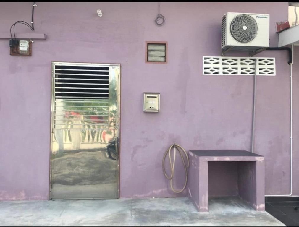a purple wall with a door and a purple table at LCS Homestay in Pangkor