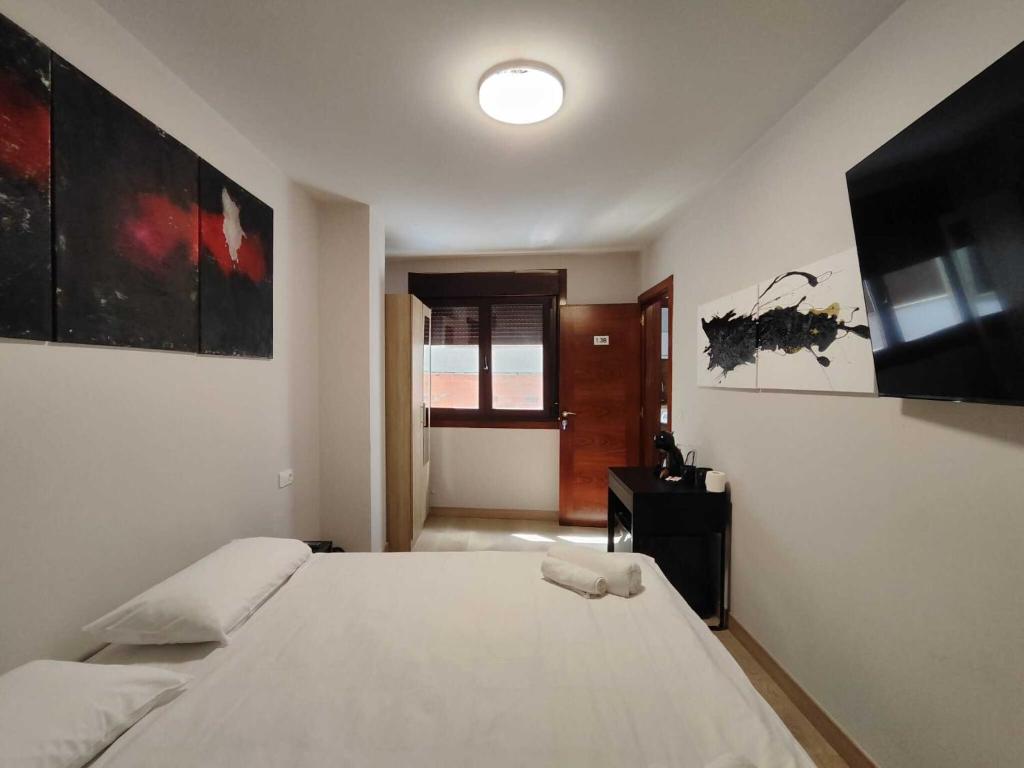 a bedroom with a large white bed and a television at Habitación dentro de la Muralla de Lugo 1.3 B in Lugo