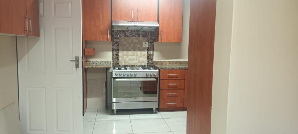 a kitchen with a stove and wooden cabinets at Melos Cosy Retreat in Ezulwini