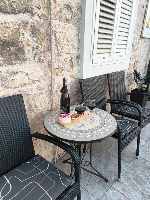 a table with a bottle and two glasses of wine at Apartman Cvitan in Zaton