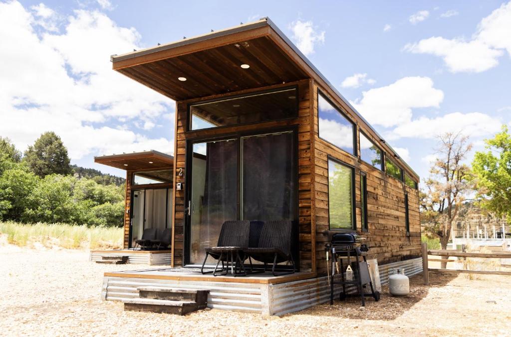a log cabin with glass doors and a chair at NEW! Modern Cabin Tiny Home at Cliffside #3 in Orderville