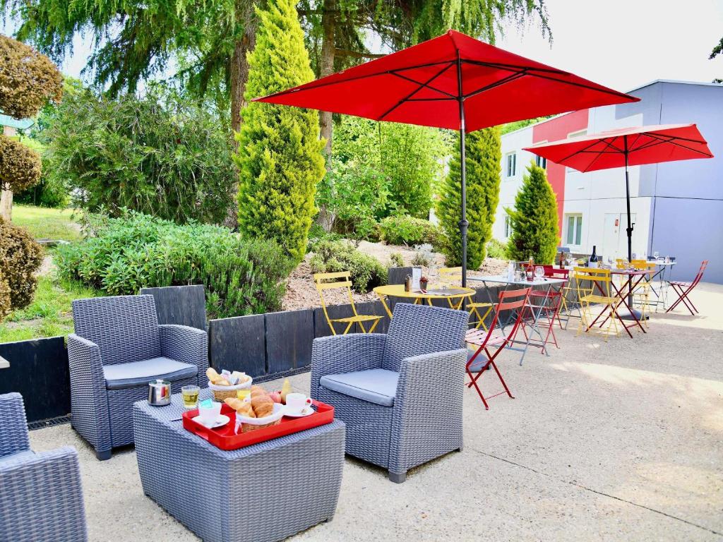 a patio with chairs and a table with a red umbrella at ibis Quimper in Quimper