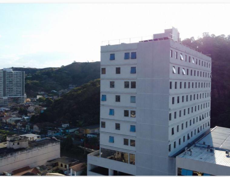 a tall white building with blue windows in a city at Hotel 3 Rios Plaza in Três Rios