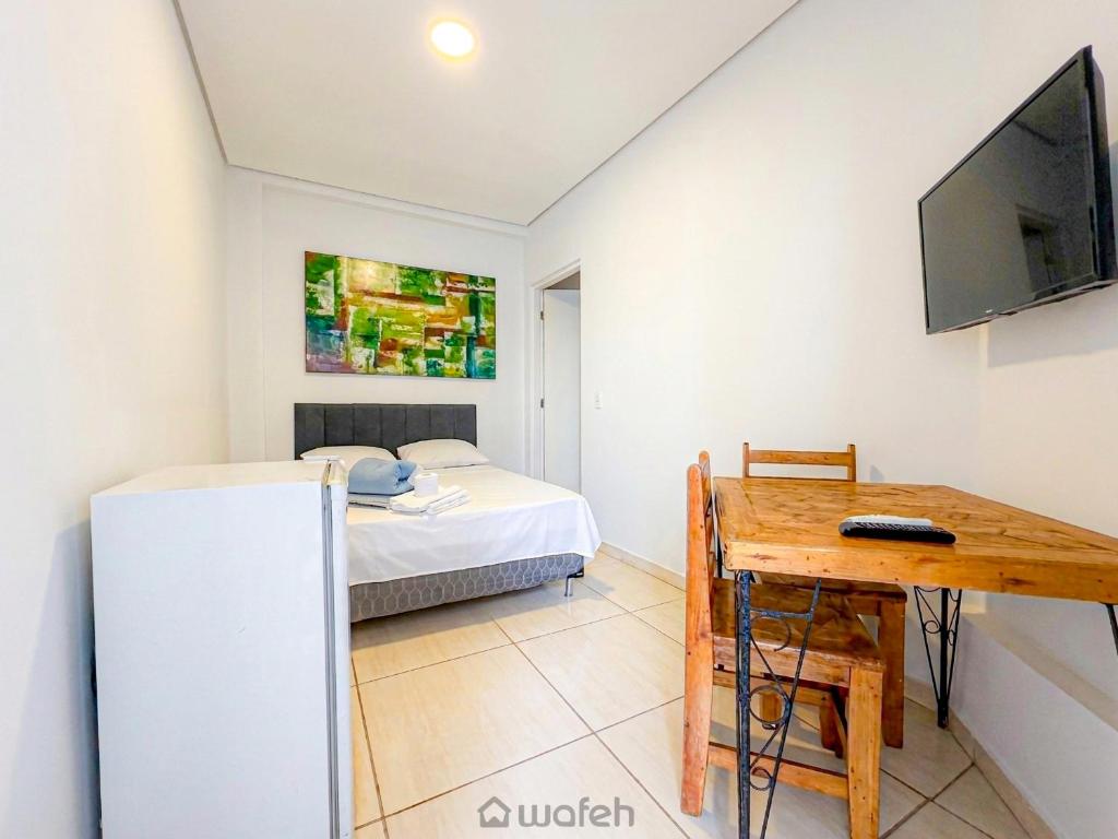 a room with a bed and a desk and a tv at Wafeh Fleming Suítes Pampulha in Belo Horizonte