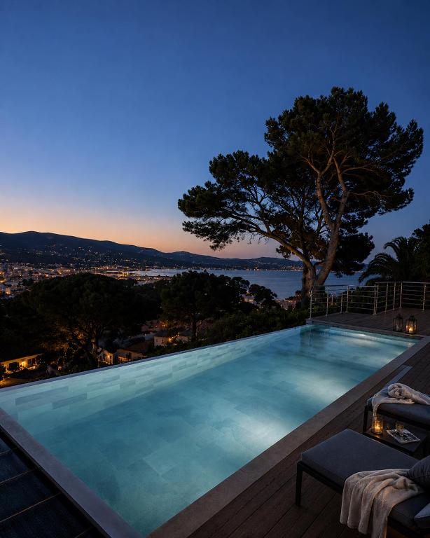 a swimming pool with a view of the ocean at night at Villa Bellevue, magnifique vue mer! Piscine chauffée, à10 mns de la plage et du centre! in Cavalaire-sur-Mer