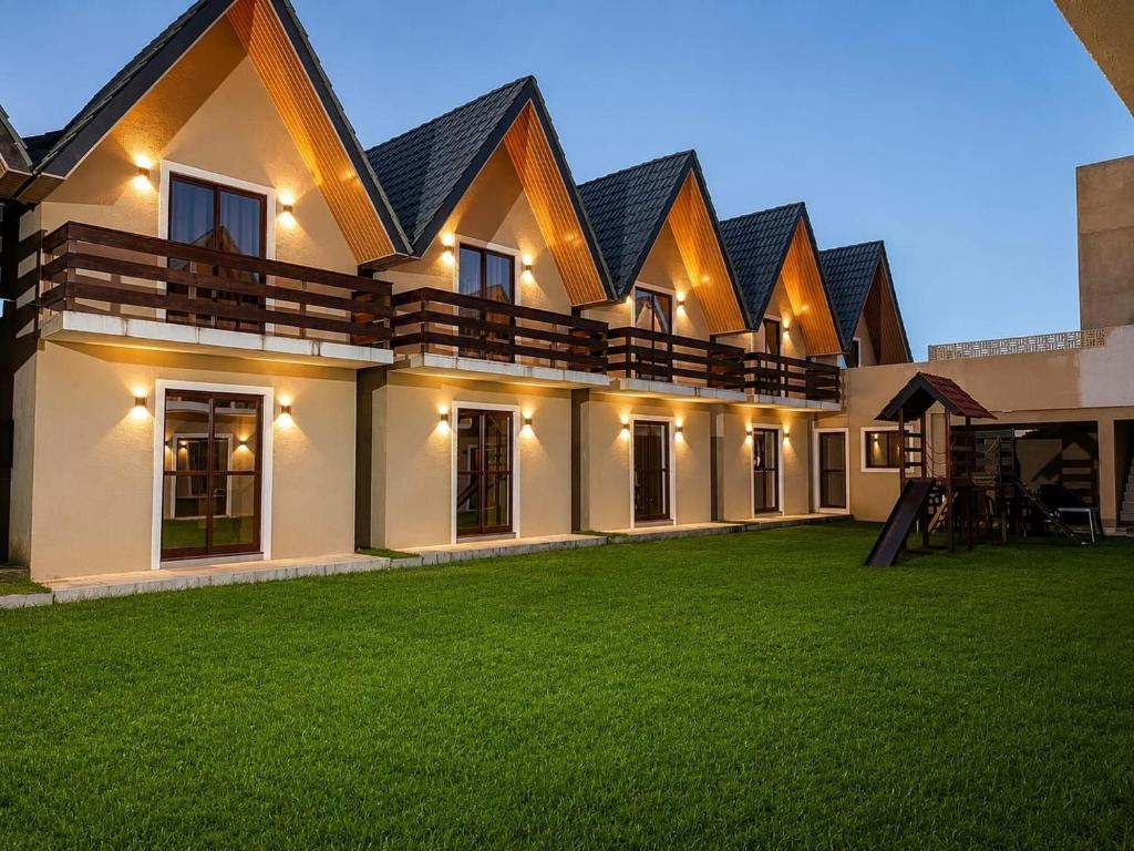 a house with a green lawn in front of it at Chalet Retreat of the Mountain in Bananeiras