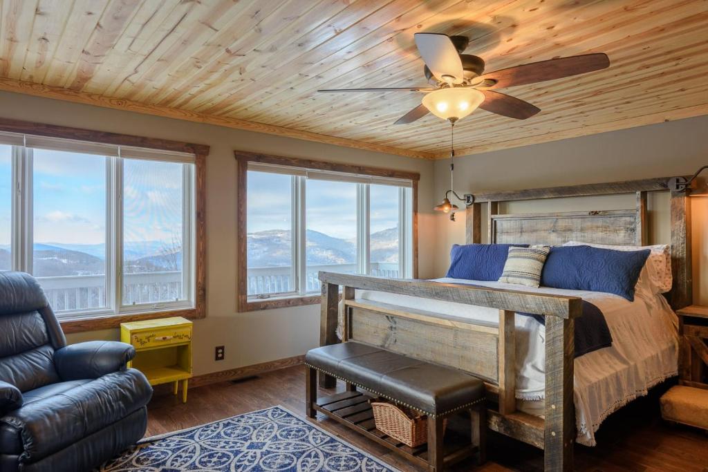 a bedroom with a bed with a ceiling fan and windows at Bear The View in Seven Devils