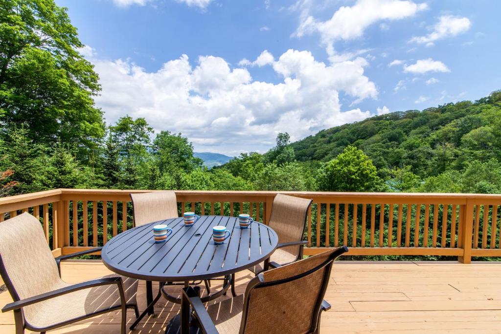 a blue table and chairs on a deck with a view at High Road Cabin in Banner Elk