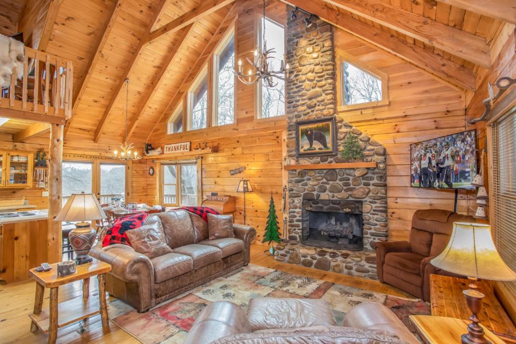 a living room with a stone fireplace in a log cabin at Sugar Bear in Sugar Mountain