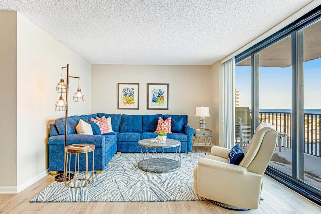 a living room with a blue couch and a balcony at Sea Colony - 302S Edgewater in Bethany Beach