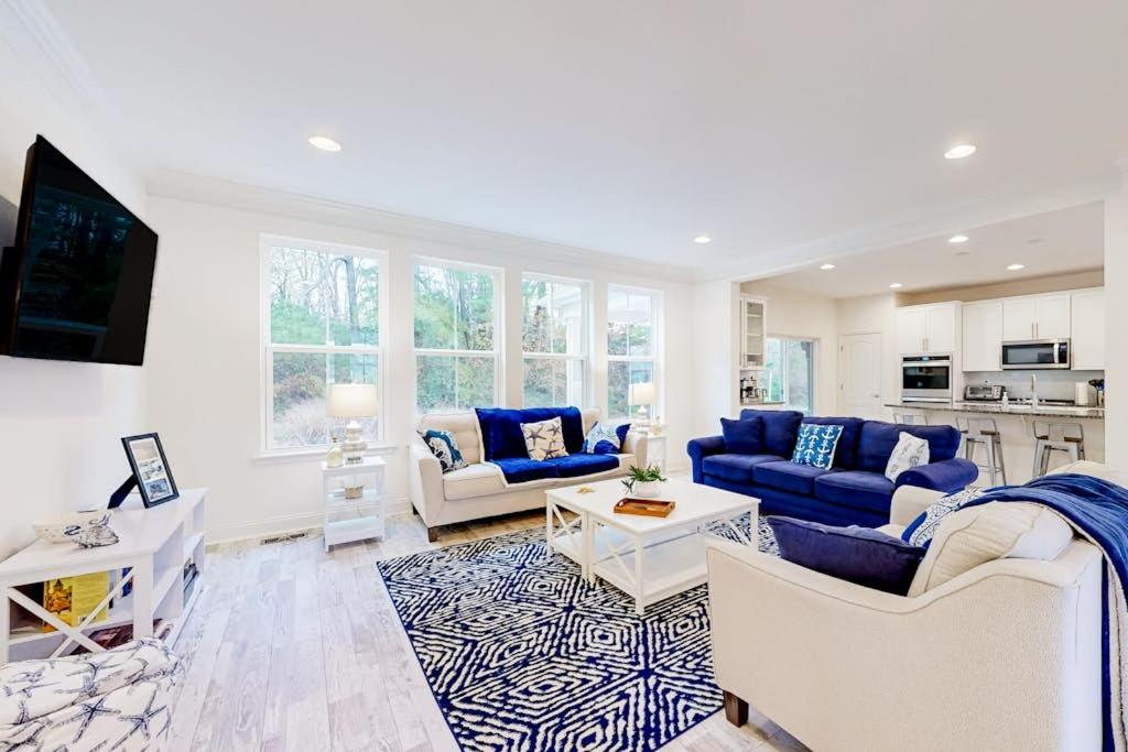 a living room with blue couches and a kitchen at The Estuary - 26643 Weathervane Way in Frankford