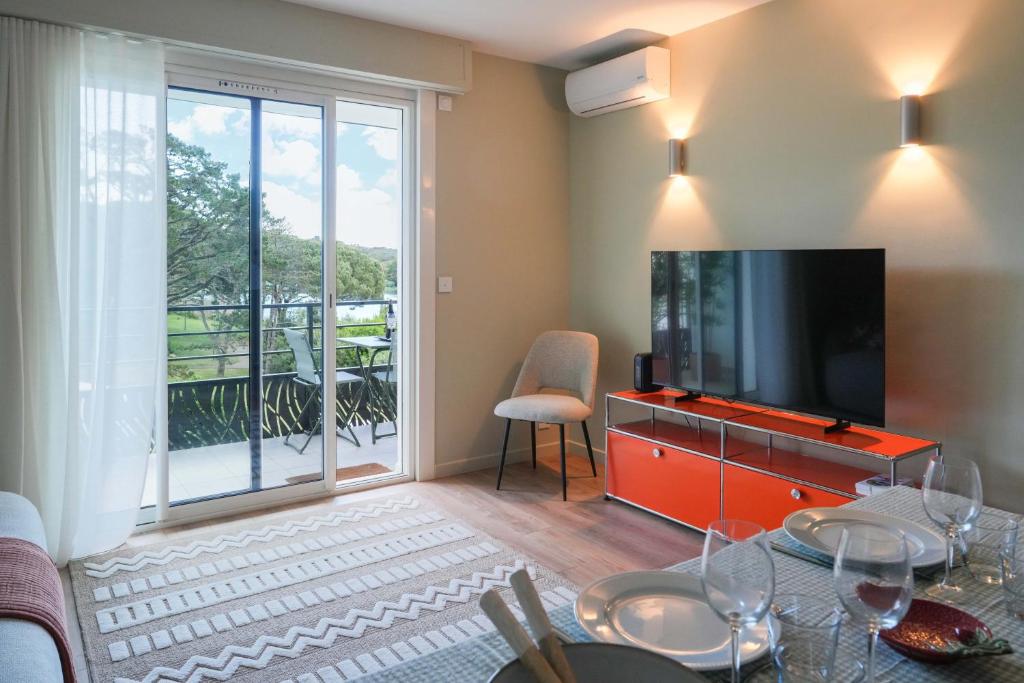 a living room with a television and a balcony at Chiberta Ocean & Golf Suite in Anglet